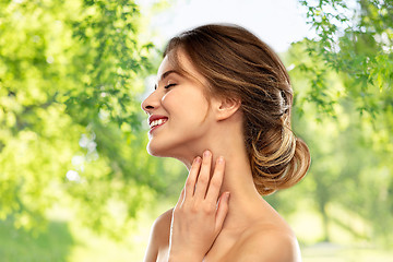 Image showing smiling young woman touching her neck