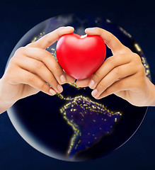 Image showing hands holding red heart over earth in space