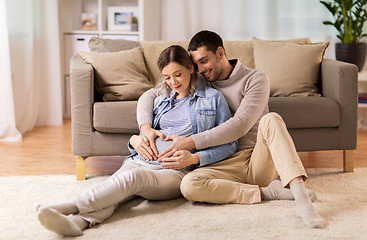 Image showing man with pregnant woman making hand heart at home