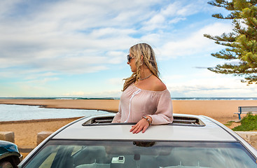 Image showing Road trip to beach. Carefree woman in sunroof with views