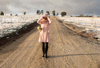 Image showing Happy go lucky woman walking down dirt road in light snow fall