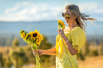 Image showing Happy woman holding sunflowers hair blowing in the wind