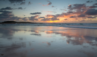 Image showing Mirrored coastal reflections in wet beach sand at sunrise