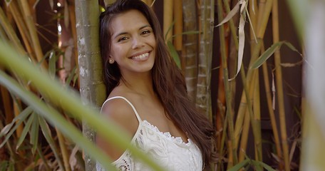 Image showing Pretty smiling woman leaning on bamboo tree