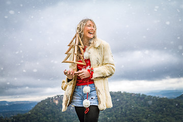 Image showing Woman holding Christmas items in snowy mountain scene