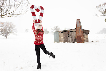 Image showing Woman holding Christmas candy canes in shape of heart in snow landscape