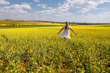 Image showing Country girl frollicking in fields of golden canola