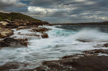 Image showing Wave action on coastal rocks with waterfall cascades