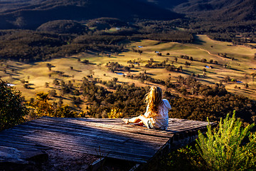 Image showing Female sitting on timber ramp taking in mountain valley veiws in