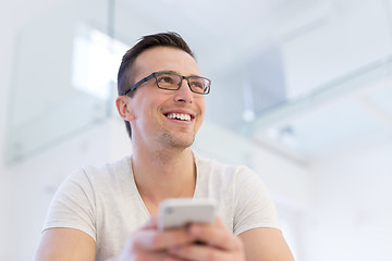 Image showing young man using a mobile phone  at home