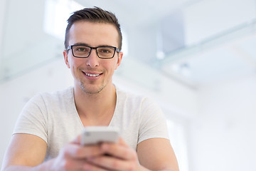 Image showing young man using a mobile phone  at home