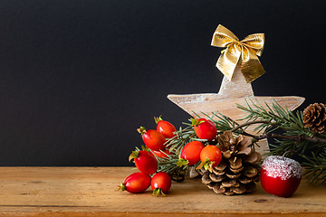 Image showing wooden Star with twig pine cone and rose hip background