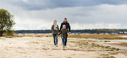 Image showing happy family walking along autumn beach