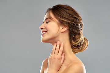 Image showing smiling young woman touching her neck