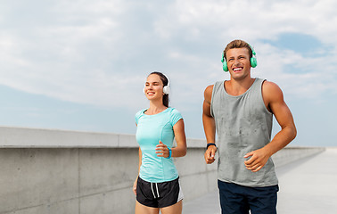 Image showing couple with headphones running outdoors