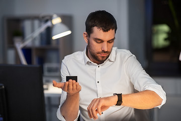 Image showing businessman using smart speaker at night office