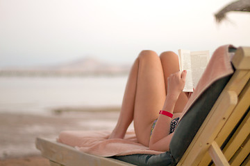 Image showing Woman reading book on the beach