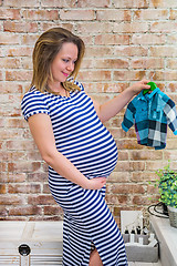 Image showing Beautiful pregnant woman sitting near wall