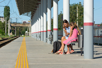 Image showing Mom and daughters are waiting for the train on the empty platform of the railway station