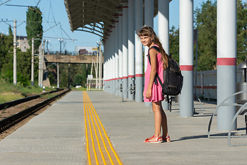 Image showing The eight-year-old girl on the platform of the railway station turned around and looked into the frame