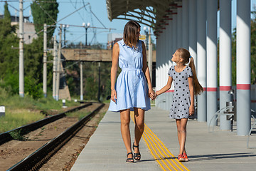 Image showing Young beautiful girl and teenage daughter walk on the empty platform of the train station