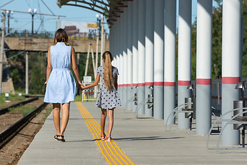 Image showing Young beautiful girl and teenage daughter walk from the camera on the empty platform of the train station