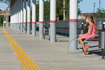 Image showing Girl waiting for a train on the empty platform of the railway station