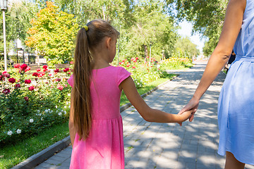 Image showing A girl walks along the alley and holds mom\'s hand