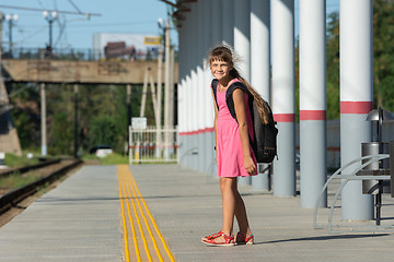 Image showing The eight-year-old girl on the platform of the train station looked funny in the frame