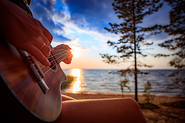 Image showing Woman at sunset holding a ukulele