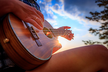 Image showing Woman at sunset holding a ukulele