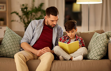Image showing father and son reading book sofa at home