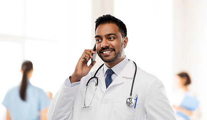 Image showing smiling indian male doctor calling on smartphone
