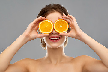 Image showing smiling woman with oranges over grey background