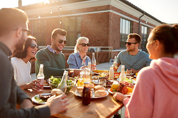 Image showing happy friends with drinks or bbq party on rooftop