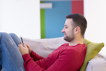 Image showing young man using a mobile phone  at home