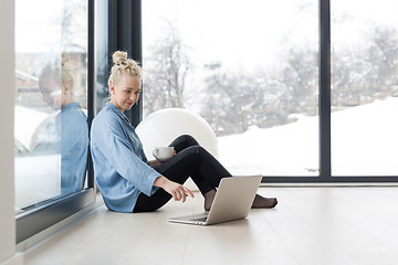 Image showing woman drinking coffee and using laptop at home