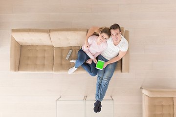 Image showing young couple in living room using tablet top view