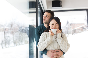 Image showing multiethnic couple enjoying morning coffee by the window