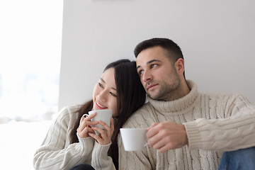 Image showing multiethnic couple enjoying morning coffee by the window