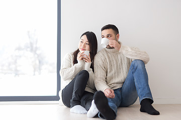 Image showing multiethnic couple enjoying morning coffee by the window