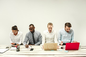 Image showing Young men and women sitting at office and working on laptops. Emotions concept