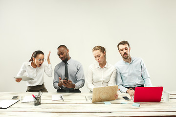 Image showing Young men and women sitting at office and working on laptops. Emotions concept