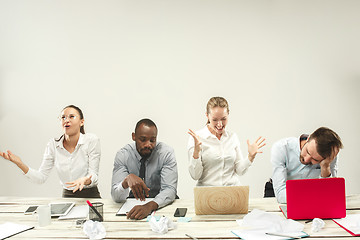 Image showing Young men and women sitting at office and working on laptops. Emotions concept