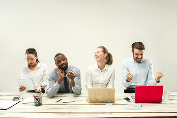 Image showing Young men and women sitting at office and working on laptops. Emotions concept