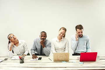 Image showing Young men and women sitting at office and working on laptops. Emotions concept