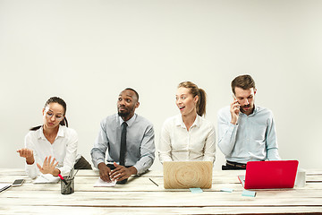 Image showing Young men and women sitting at office and working on laptops. Emotions concept