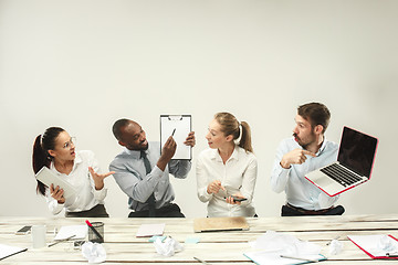 Image showing Young men and women sitting at office and working on laptops. Emotions concept