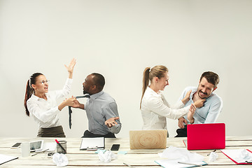 Image showing Young men and women sitting at office and working on laptops. Emotions concept