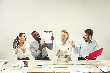 Image showing Young men and women sitting at office and working on laptops. Emotions concept